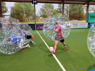 Two players in air balls play soccer on artificial turf.