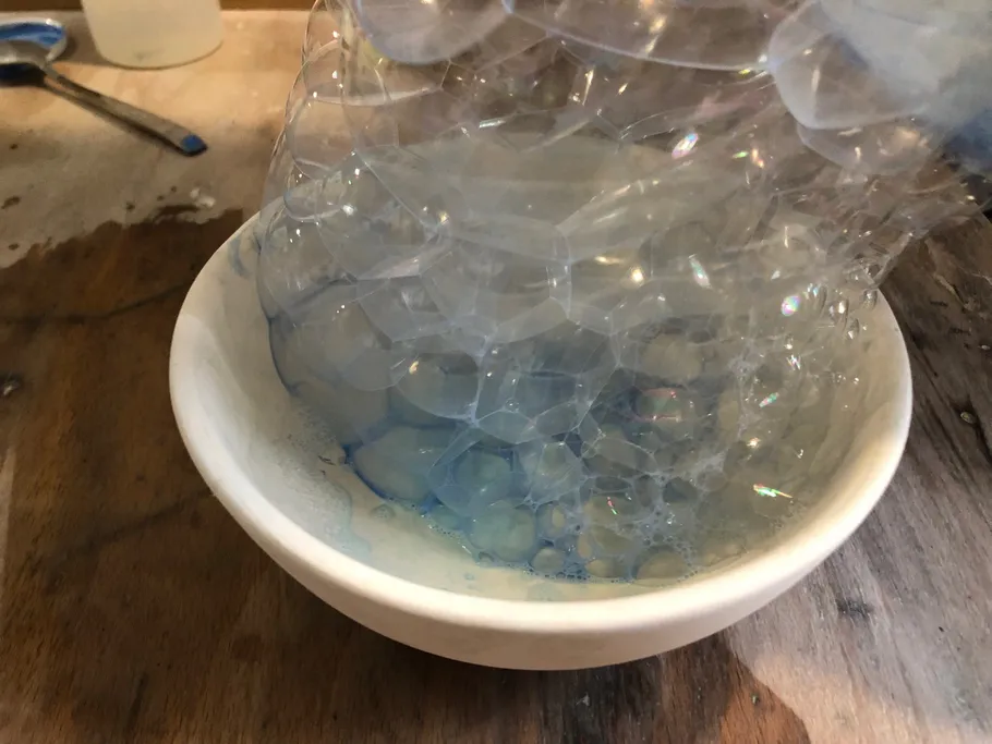 Bubbles rising from a white bowl on table.
