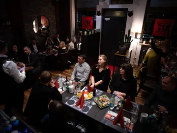 Group of guests in the restaurant are watching a waiter.