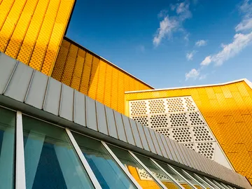 Yellow building façade reflects sunlight under a blue sky.