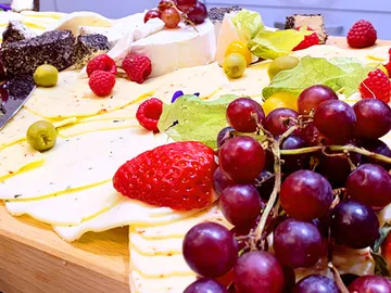 Cheese platter with various fruits and decorative leaves.