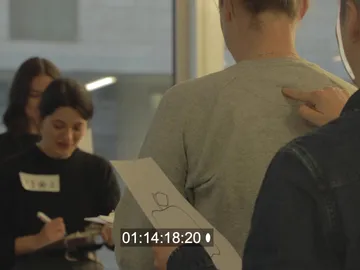 A person with a grey shirt receives instructions in a workshop.