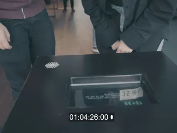 Table with time measurement, two people are looking at it with interest.