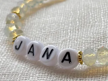 Perlenarmband mit dem Namen „JANA“ auf einem Stoffuntergrund.