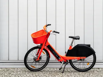 Orangenes Fahrrad steht an einer grauen Wand ohne Bewegung.