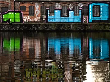 Colourful graffiti on an outer wall of a building, reflected in the water.