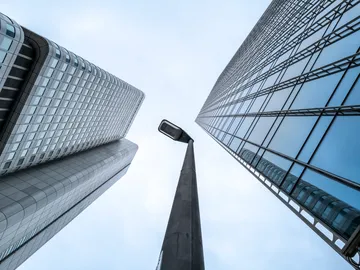 Hohe Gebäude stehen neben einer Straßenlaterne, Himmel sichtbar.