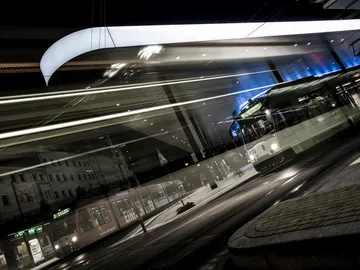 Tram travels quickly through an illuminated train station.