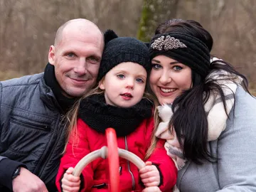 Familie lächelt, während sie im Freien zusammen posiert.