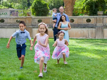 Children running on grass with family in background.