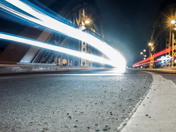 Bright lights move quickly across a bridge at night.