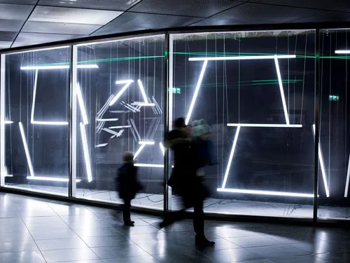 A bright light installation is viewed and avoided by passers-by.