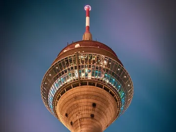 Ein hoher Turm leuchtet in der Dunkelheit der Nacht.