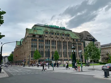 Historisches Gebäude mit grüner Dachfläche, auf belebter Straße.