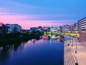 Fluss reflektiert Stadtbeleuchtung während des Sonnenuntergangs.