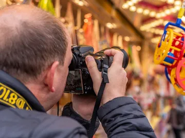 Ein Mann fotografiert bunte Objekte auf einem Jahrmarkt.