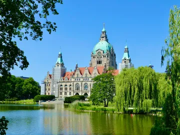Historisches Gebäude spiegelt sich im ruhigen Wasser eines Parks.