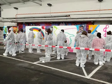 Group of people spraying on white walls in overalls.