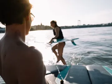 Junge beobachtet Mädchen, das auf Wasser steht und surft.