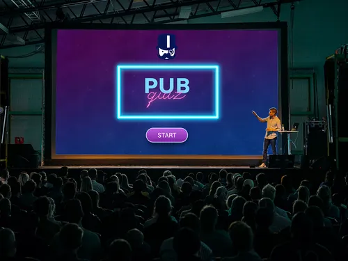 Großes Bildschirm zeigt `PUB Quiz`, Presenter erklärt das Spiel.