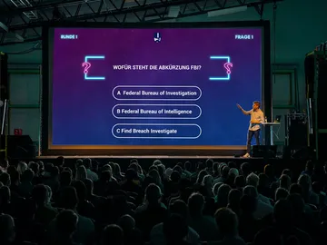 A quiz leader presents questions on a big screen.