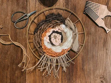 Wandbehang aus Garn kreiert, auf Holztisch gelegt.