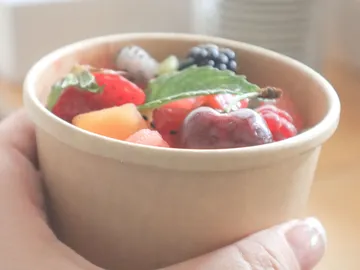 Eine Hand hält eine Schale mit frischen Früchten.