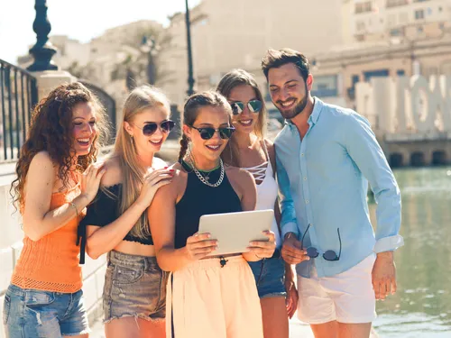 Group of friends looking at tablet outdoors.