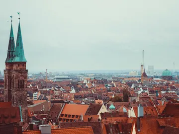 Stadtansicht mit roten Dächern und hohen Kirchen.