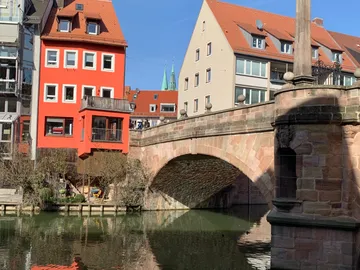 Colourful houses surround a stone bridge over water.