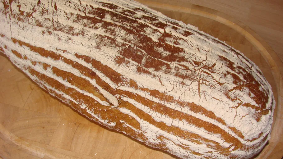 Ein Brot liegt auf einem Holzbrett, ungeschnitten.