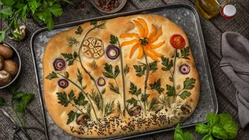 Ein bunten Brot mit essbaren Blumen und Kräutern dekoriert.