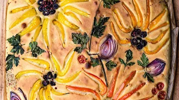Brot mit buntem Gemüse, kunstvoll gestaltet auf Holzbrett.