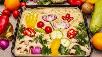Vegetables on dough, artfully arranged, ready to bake.