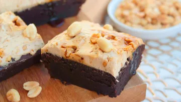 Brownie mit Erdnussbutter-Creme auf einem Holzbrett, genussbereit.