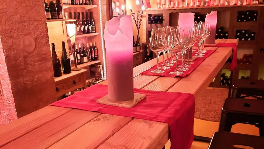 Weinkeller mit Gläsern und Tisch bei Kerzenschein.