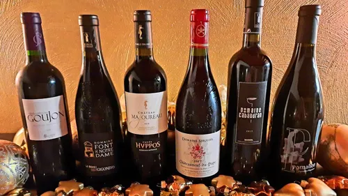 Six wine bottles are placed on a table, surrounded by decoration.