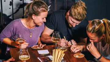 Friends draw and laugh while having drinks at the table.