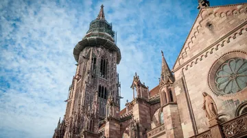 High church tower with scaffolding under a blue sky.