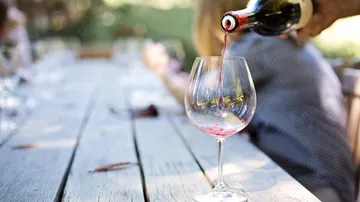 Wine glass is filled with red wine on a table.