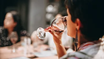 A person drinks wine in a sociable setting.
