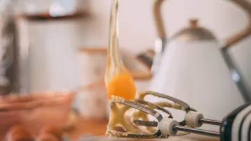 Eggs are whipped using a hand mixer in a kitchen.
