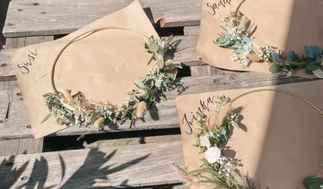 Three wreaths lie on brown paper on the wooden surface.