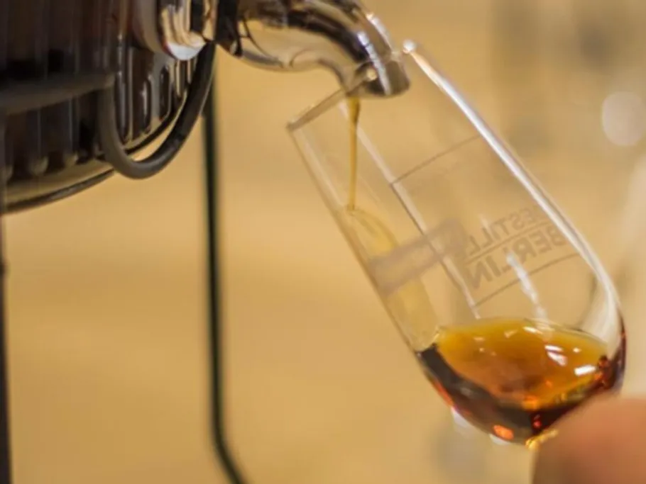 Ein Glas wird mit einer dunklen Flüssigkeit gefüllt.