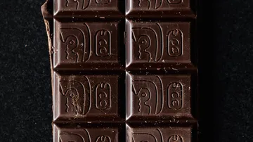 Dark chocolate with engraved patterns lies on a black background.