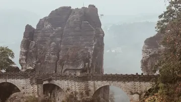 Felsen sind umgeben von Nebel und einer Brücke.