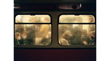 Blurred windows, people sitting on a crowded train.