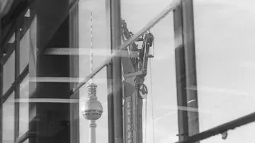 Towers reflect in the window, construction is visible in the background.