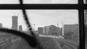 From a window you can see a view of the city with railroad tracks.