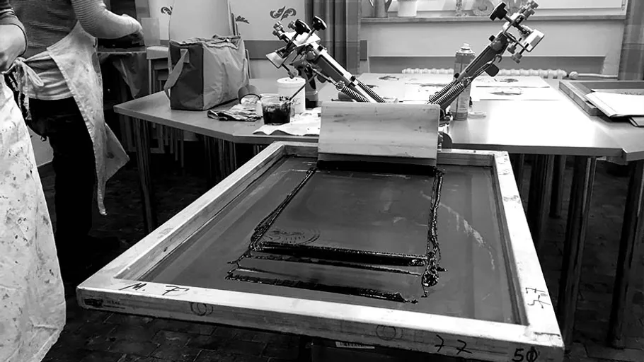 Siebdruckmaschine druckt auf einem Tisch in einem Atelier.